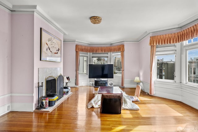 living room featuring crown molding, plenty of natural light, wood finished floors, and a high end fireplace