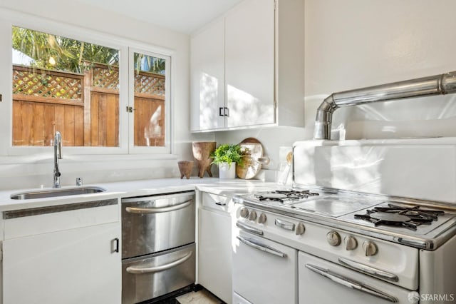 kitchen featuring dishwashing machine, sink, double oven range, and white cabinets