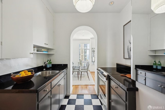 1101 Green St Unit 1402, San Francisco, CA 94109 - kitchen with dark countertops, tile patterned floors, a sink, stainless steel electric stove, and arched walkways