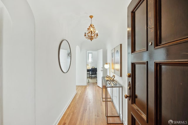 1101 Green St Unit 1402, San Francisco, CA 94109 - hallway with light wood finished floors, a chandelier, baseboards, and arched walkways