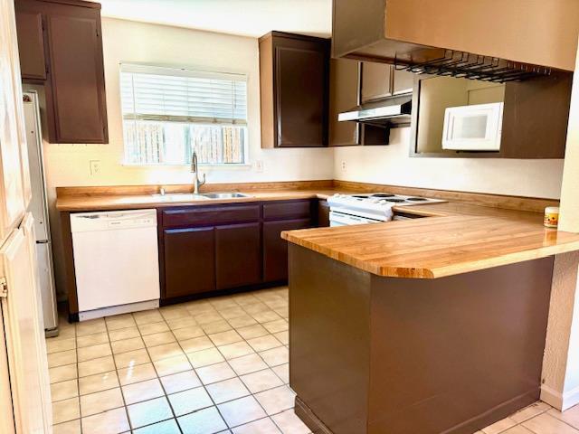80 Portola Way Unit 105, Tracy, CA 95376 - kitchen with white appliances, a sink, under cabinet range hood, a peninsula, and butcher block countertops