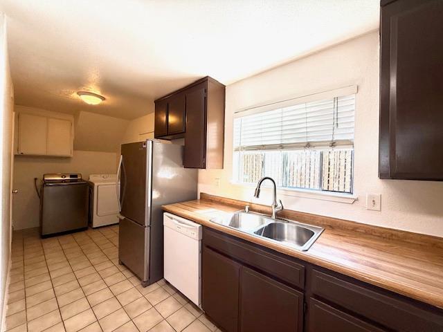 80 Portola Way Unit 105, Tracy, CA 95376 - kitchen featuring white dishwasher, washer and clothes dryer, a sink, light tile patterned floors, and dark brown cabinetry