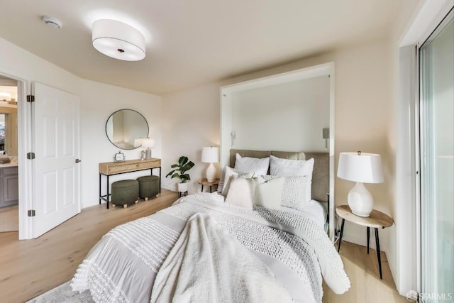 bedroom with ensuite bathroom and light wood-type flooring