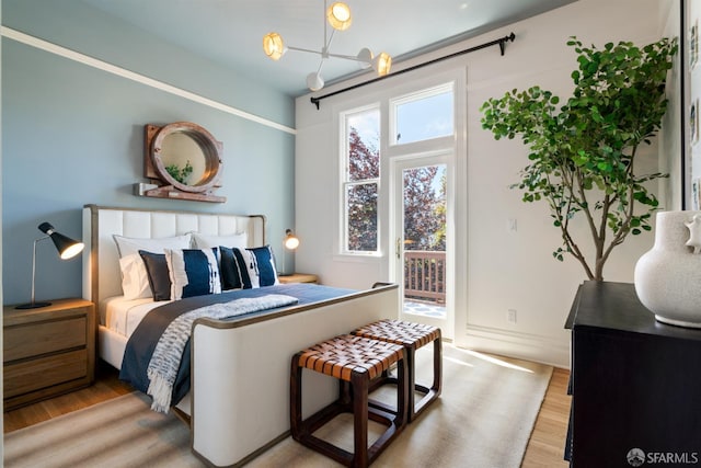 49 Hill St, San Francisco, CA 94110 - bedroom with wood finished floors, access to exterior, and a chandelier