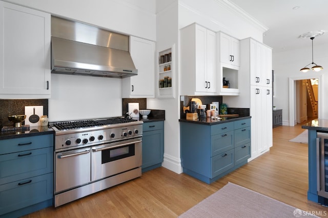 49 Hill St, San Francisco, CA 94110 - kitchen with double oven range, wall chimney range hood, blue cabinetry, ornamental molding, and dark countertops