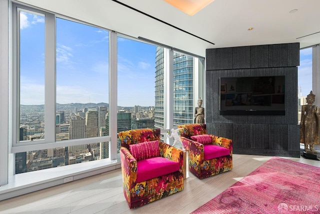 living room featuring hardwood / wood-style floors, expansive windows, and a tiled fireplace