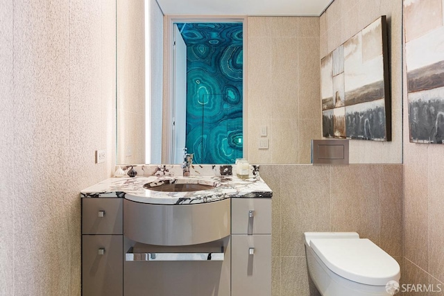 bathroom with vanity, toilet, and tile walls