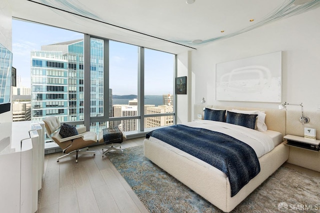 bedroom with wood-type flooring and a wall of windows