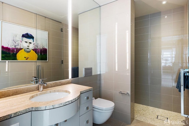 bathroom featuring vanity, a shower, tile patterned flooring, toilet, and tile walls