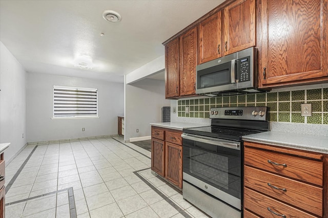 kitchen featuring decorative backsplash, light tile patterned floors, and appliances with stainless steel finishes