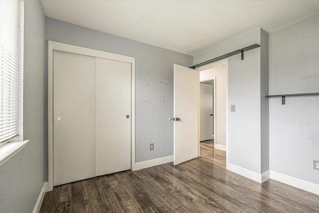 unfurnished bedroom with a closet and dark hardwood / wood-style floors