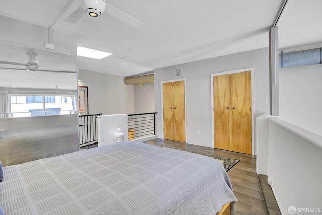 bedroom with ceiling fan, visible vents, and wood finished floors