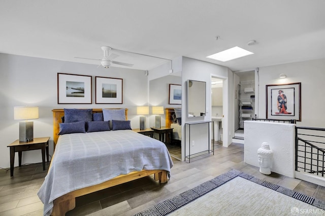 bedroom with light wood-type flooring, a skylight, and a ceiling fan