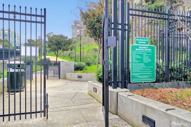 view of gate with central AC and fence