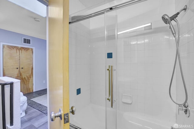 full bathroom featuring visible vents, shower / bath combination with glass door, and wood finished floors