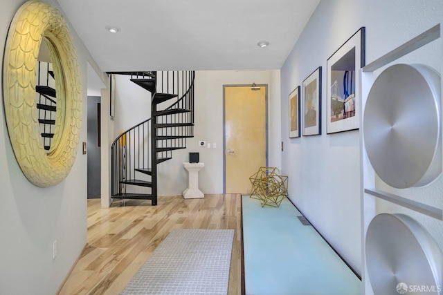 hallway featuring light wood-style flooring, stairs, and recessed lighting