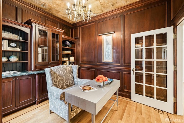 office space with built in shelves, wooden walls, a chandelier, and light wood-type flooring