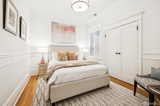 bedroom with crown molding, a closet, and light hardwood / wood-style flooring