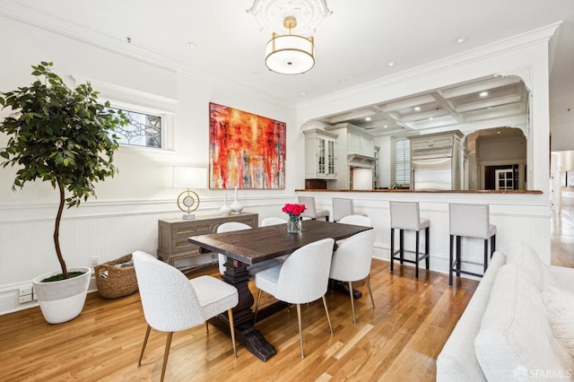 dining area featuring coffered ceiling, ornamental molding, beamed ceiling, and light wood-type flooring