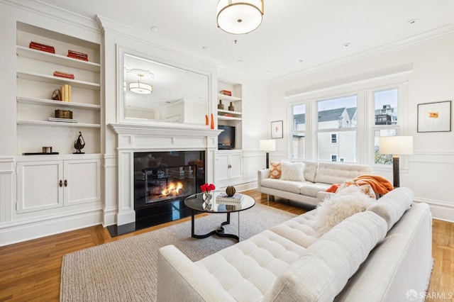 living room with crown molding, built in features, and light hardwood / wood-style flooring