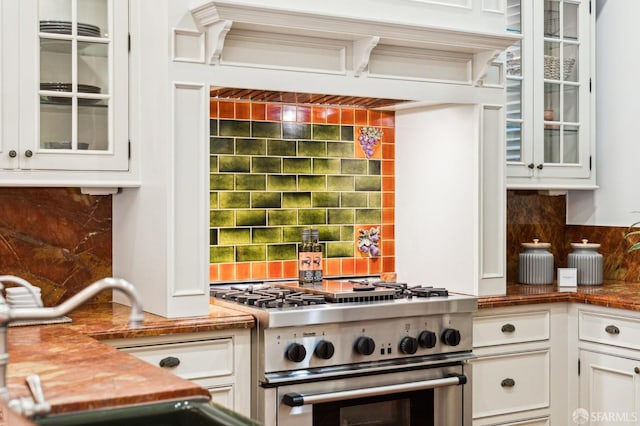 kitchen with backsplash, high end stainless steel range, and white cabinets