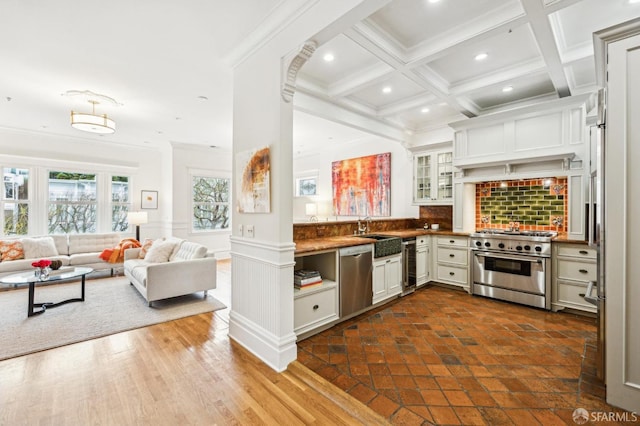 kitchen featuring wine cooler, ornamental molding, stainless steel appliances, beam ceiling, and white cabinets