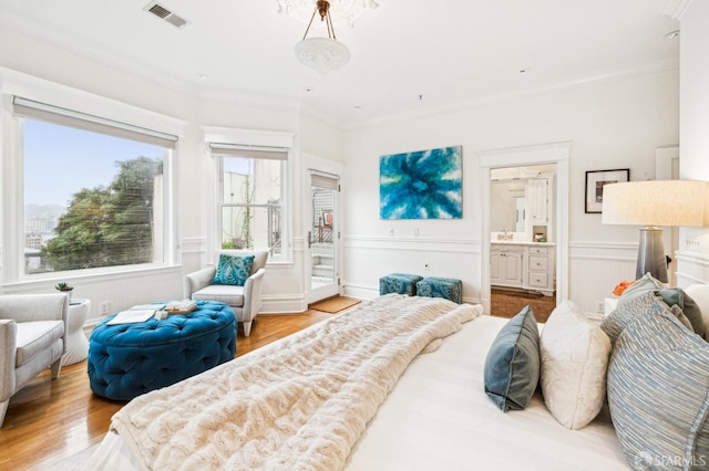 bedroom with connected bathroom, hardwood / wood-style floors, and ornamental molding