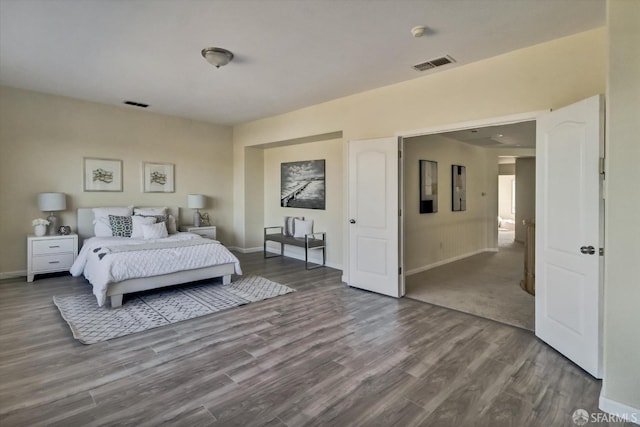 bedroom featuring baseboards, visible vents, and wood finished floors