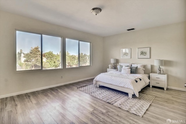 bedroom featuring light wood-type flooring, visible vents, and baseboards