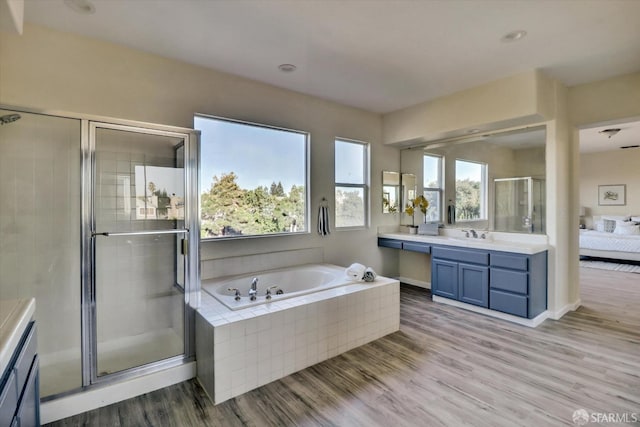 ensuite bathroom featuring wood finished floors, a garden tub, vanity, and a shower stall