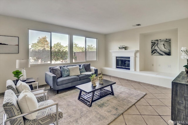 living room with visible vents, a glass covered fireplace, and light tile patterned flooring