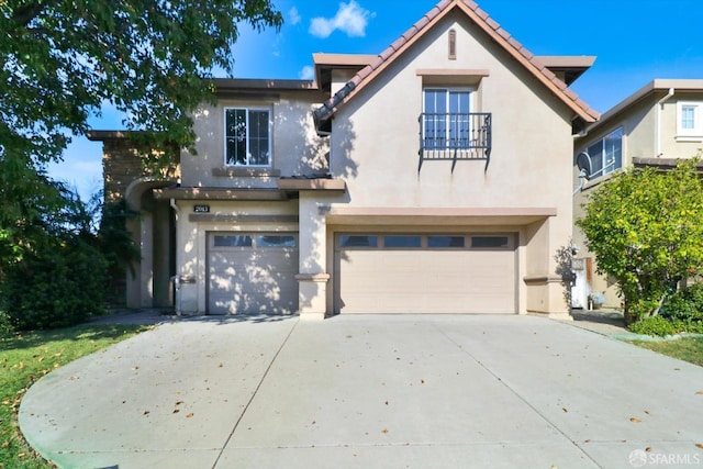 view of front of home featuring an attached garage, a balcony, driveway, a tiled roof, and stucco siding