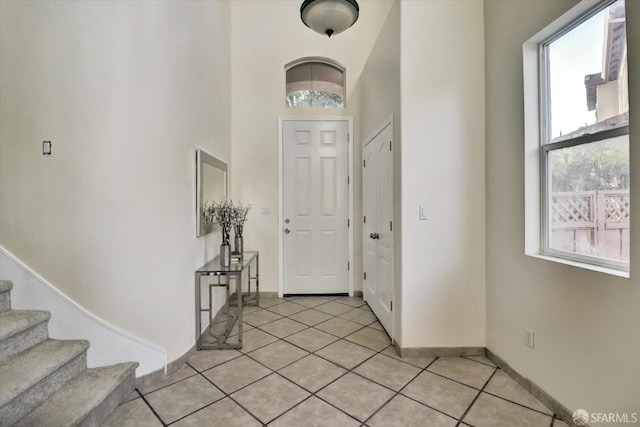 entryway with stairs, light tile patterned flooring, and baseboards