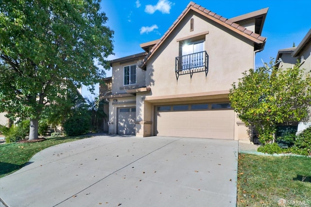 mediterranean / spanish house with an attached garage, a balcony, concrete driveway, a tiled roof, and stucco siding