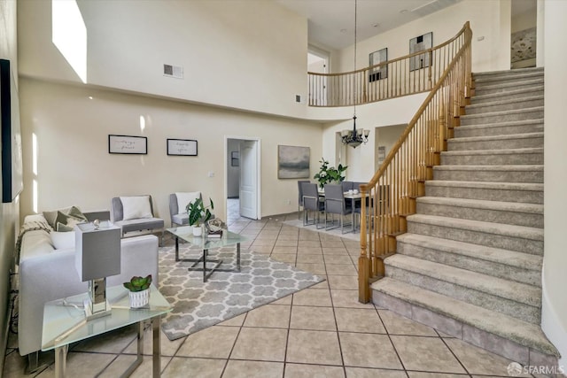 tiled living room with stairway, a towering ceiling, visible vents, and an inviting chandelier