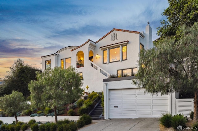 mediterranean / spanish house with an attached garage, stucco siding, concrete driveway, and stairs
