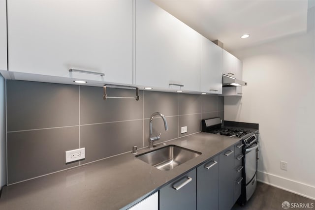 kitchen with tasteful backsplash, stainless steel gas stove, a sink, white cabinetry, and under cabinet range hood