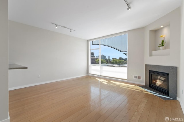 1600 Webster St Unit 409, San Francisco, CA 94115 - unfurnished living room featuring track lighting, wood-type flooring, baseboards, and a fireplace with flush hearth