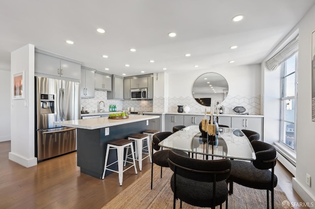 dining room featuring dark wood-type flooring, sink, a healthy amount of sunlight, and a baseboard heating unit