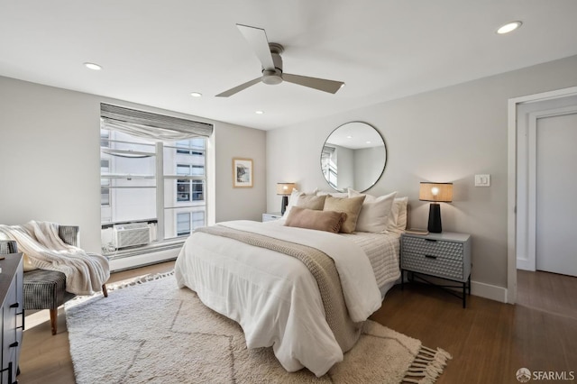 bedroom featuring a baseboard heating unit, dark hardwood / wood-style floors, ceiling fan, and cooling unit