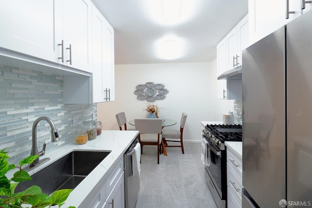 kitchen featuring sink, appliances with stainless steel finishes, white cabinetry, backsplash, and light stone countertops