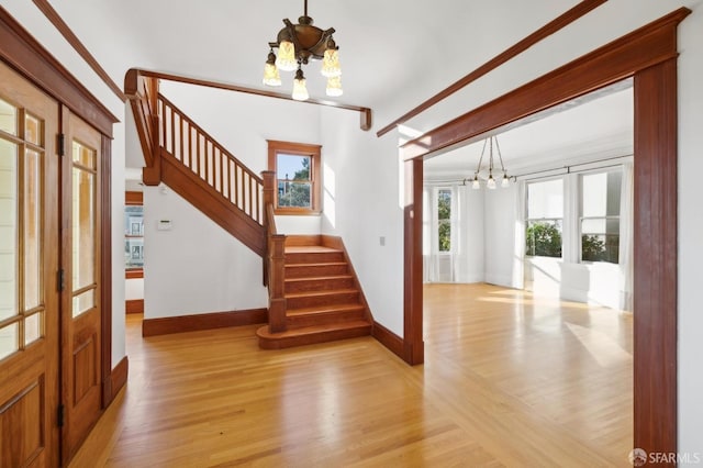 foyer featuring stairs, baseboards, light wood-type flooring, and a chandelier