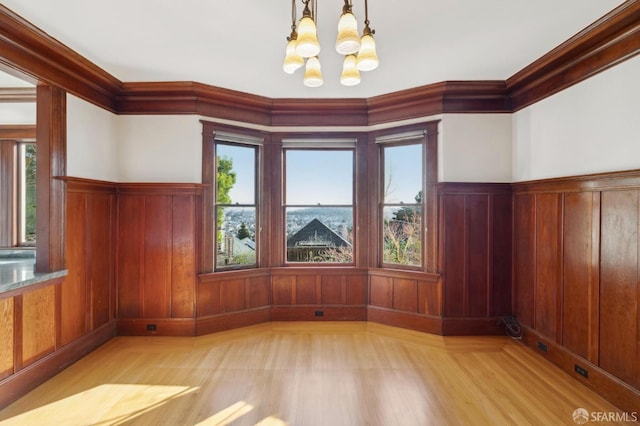 unfurnished dining area with a wainscoted wall, a healthy amount of sunlight, and an inviting chandelier