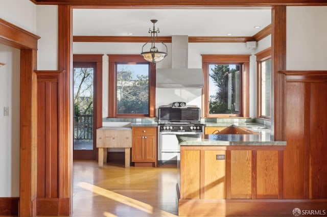 kitchen featuring light wood finished floors, crown molding, wall chimney range hood, pendant lighting, and gas stove