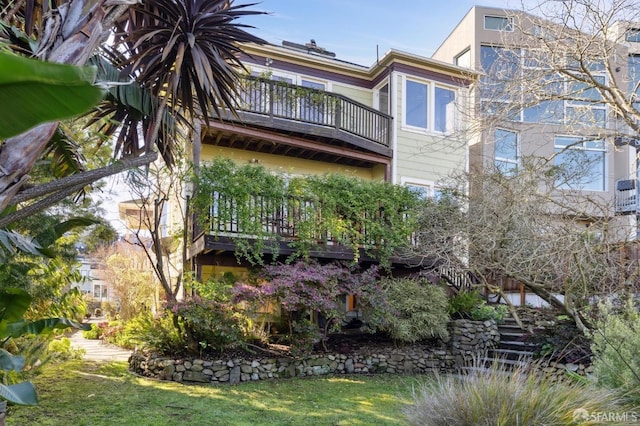 exterior space featuring stairs, a lawn, and a balcony