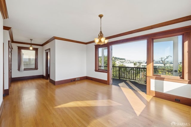 unfurnished room featuring ornamental molding, baseboards, an inviting chandelier, and wood finished floors