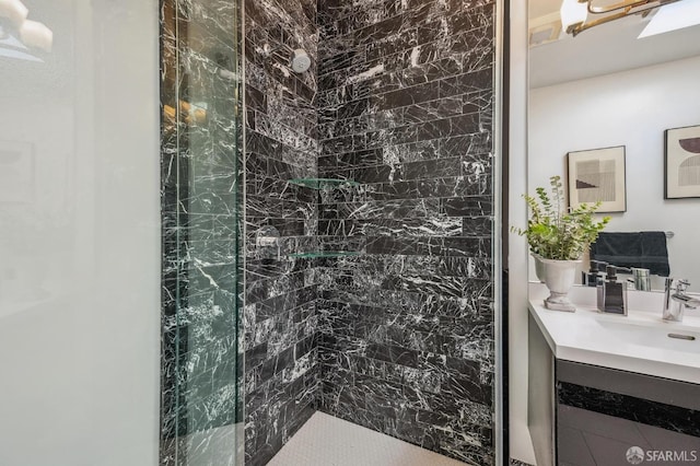 bathroom with a tile shower and vanity