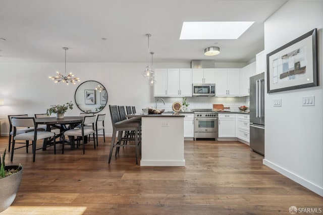 kitchen with white cabinetry, pendant lighting, a breakfast bar area, and premium appliances