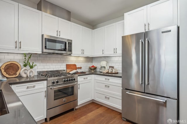 kitchen featuring tasteful backsplash, white cabinets, and premium appliances