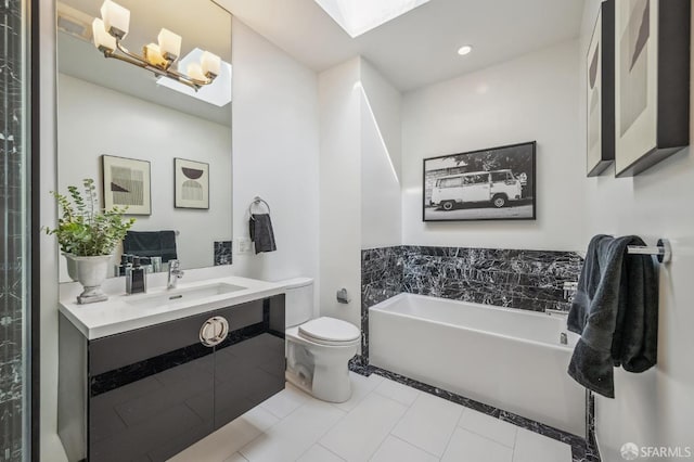 bathroom featuring a skylight, vanity, toilet, a bath, and tile patterned floors